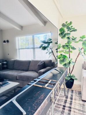 A modern living room with a sofa, a coffee table, a potted plant, and a large mirror. - Cozy 2-bedroom house. Experience Sarasota Living Near America’s Top-Rated Beach (Sarasota)