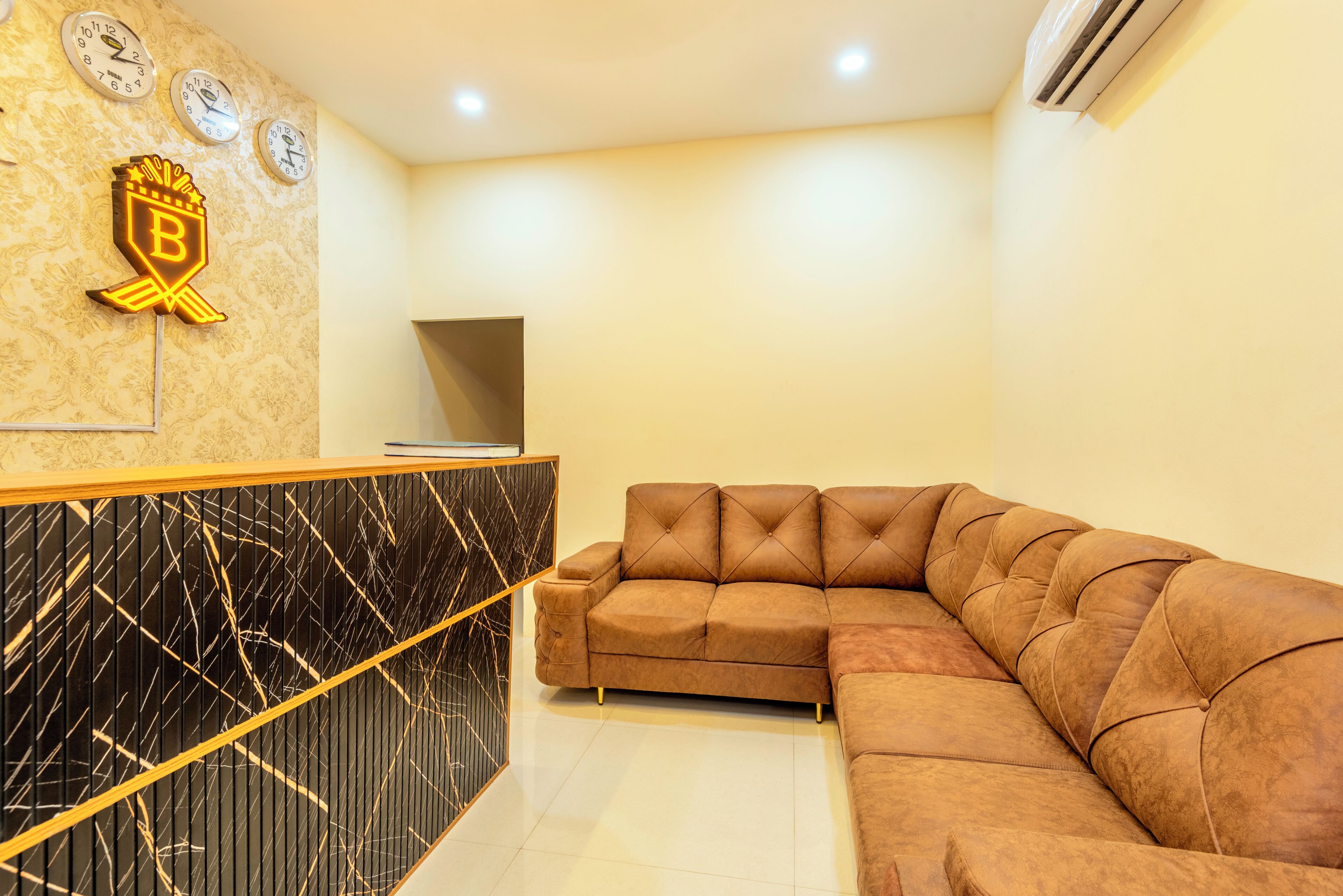 A reception area with a black marble counter, a brown leather sofa, and a wall with clocks and a logo.