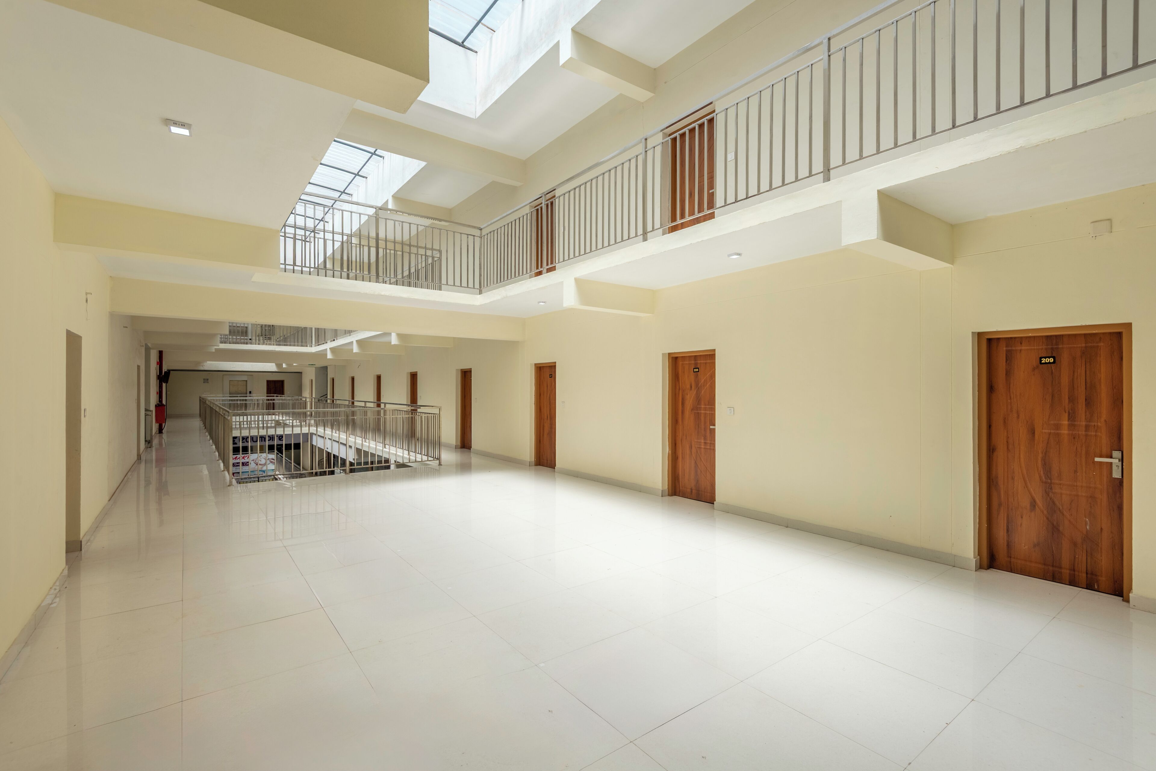 A spacious, multi-level interior with a central corridor, wooden doors, and a balcony with metal railings.