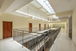 Um interior em vários níveis, com uma escadaria central, corrimãos e um claraboia.