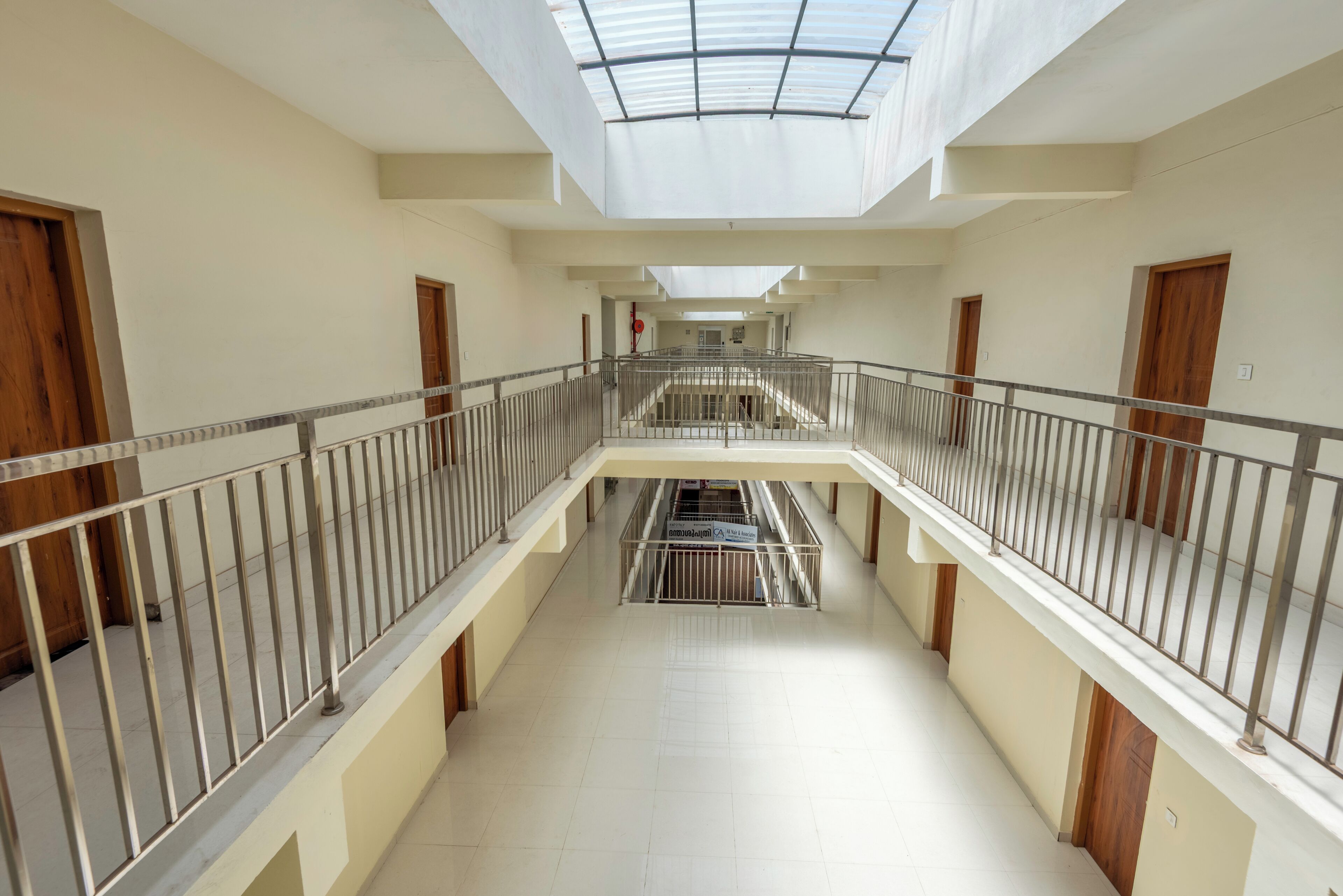 A multi-level corridor with a skylight, metal railings, and a central staircase.