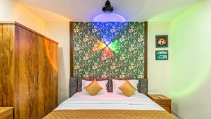 Un dormitorio con cama, armario de madera, papel tapiz floral y dos cuadros colgados en la pared.