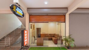 Una recepción de hotel con un mostrador, una escalera y un cartel que indica las habitaciones.