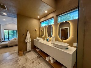 Une salle de bain moderne dotée d’un grand meuble-lavabo, de deux miroirs et offrant une vue sur l’extérieur.