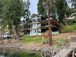 A multi-story house with a dock and a wooden staircase leading to a deck.