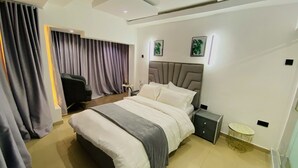 Una habitación de hotel moderna con una cama grande, una mesita de noche, una silla y un escritorio.