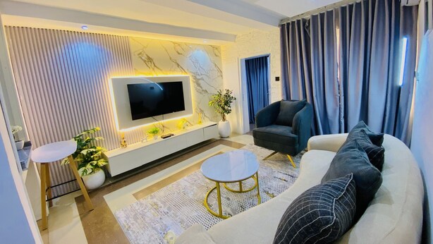 Una sala moderna con una televisión de pantalla plana, un sofá, una silla y una mesita de centro.