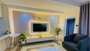 Una sala de estar moderna con un televisor de pantalla plana, un sofá, una mesa de centro y plantas decorativas.