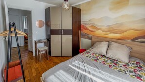 Un dormitorio con cama, armario, escritorio y lámpara colgante.