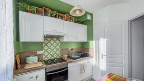 Una cocina con gabinetes blancos, salpicadero verde, encimera de madera y mantel colorido.