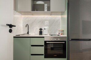 Une cuisine moderne équipée d’un four Bosch, d’un réfrigérateur en acier inoxydable et d’un micro-ondes placé sur l’étagère supérieure.