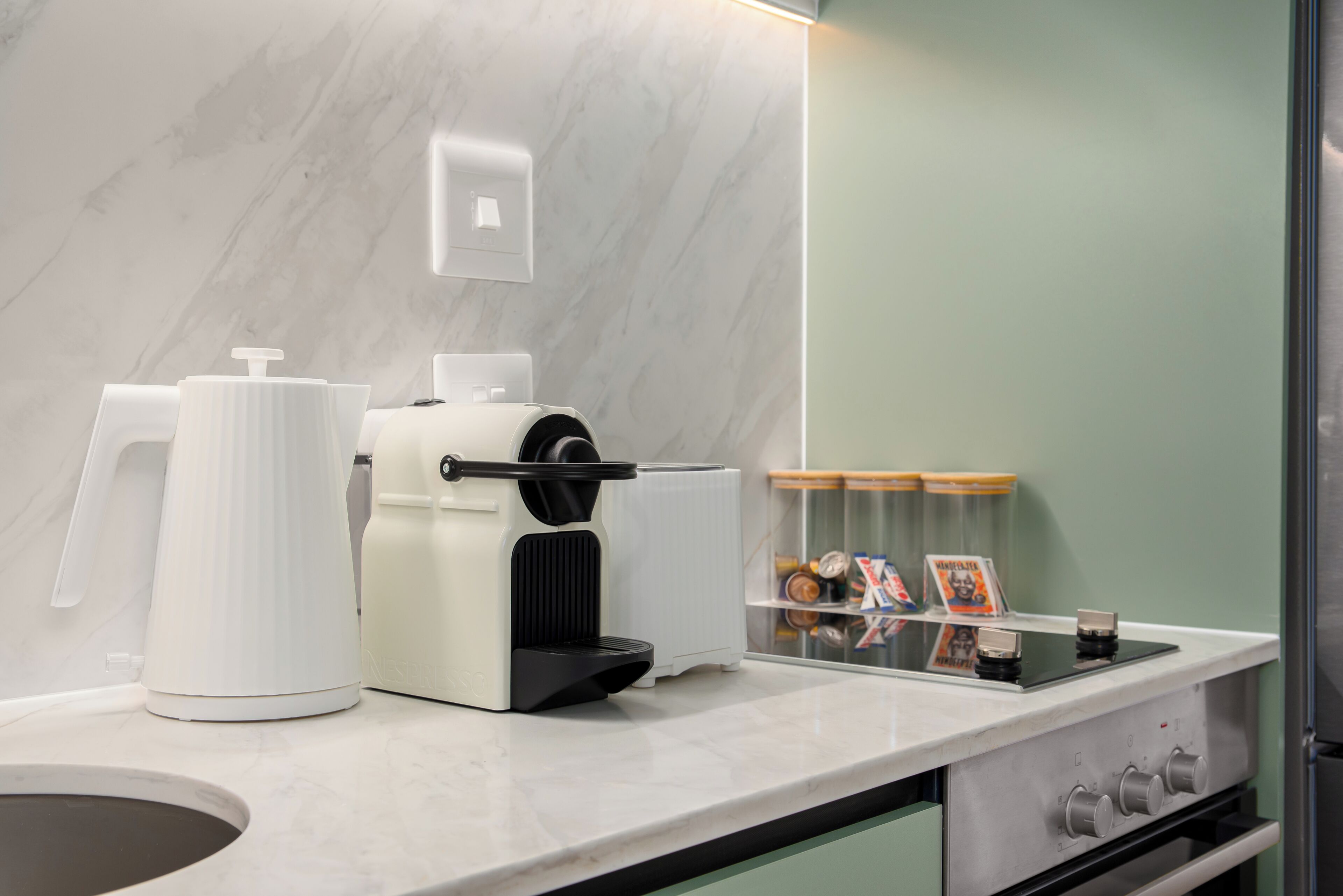 Une cuisine moderne équipée d’une machine à café, d’une bouilloire et d’un grille-pain sur le plan de travail.