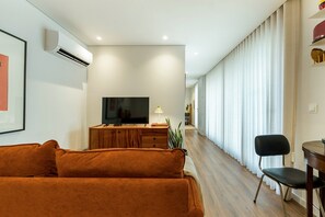 Ein modernes Wohnzimmer mit einer Couch, einem Fernseher und einem Essbereich mit einem Sessel.