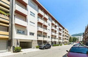 Un immeuble résidentiel à plusieurs étages, doté de balcons, d’un espace de stationnement et surplombant un ciel dégagé.