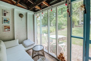 A room with a bed, a small stool, and a table with chairs outside a large glass door. - The Mariposa: Walk Downtown + Free Parking (Staunton)