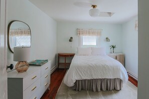 Ein Schlafzimmer mit Bett, Kommode, Nachttischen und Deckenventilator.