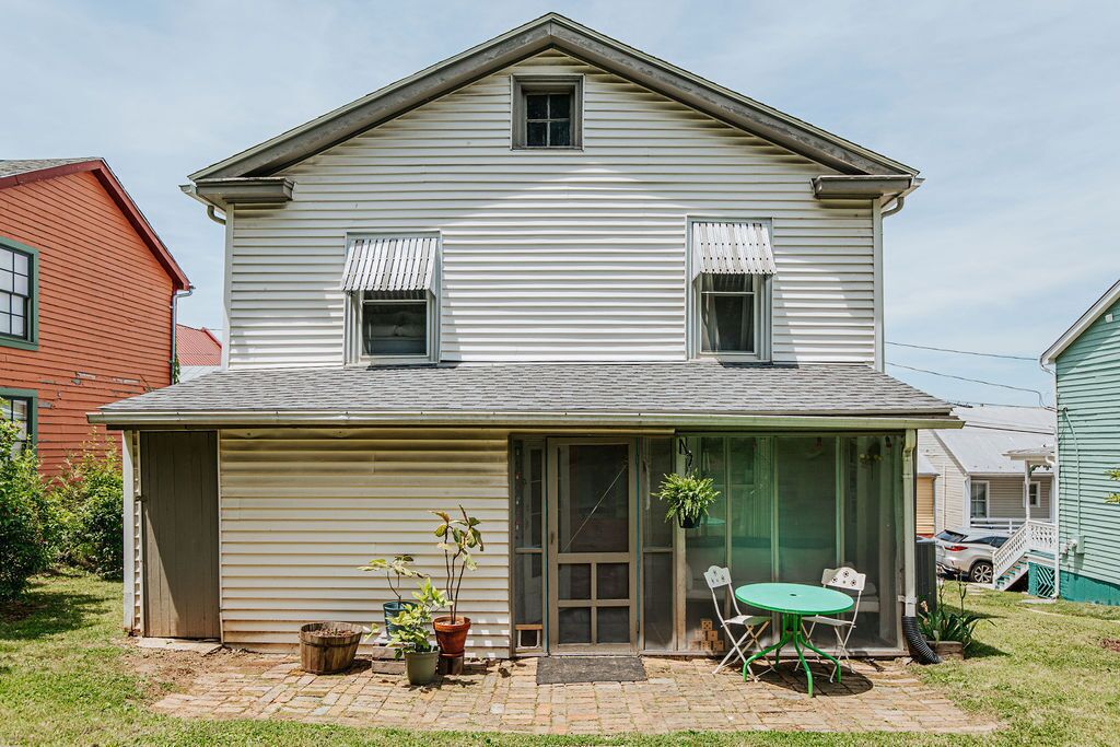 A two-story house with a covered patio, a garage, and a small front yard with potted plants.