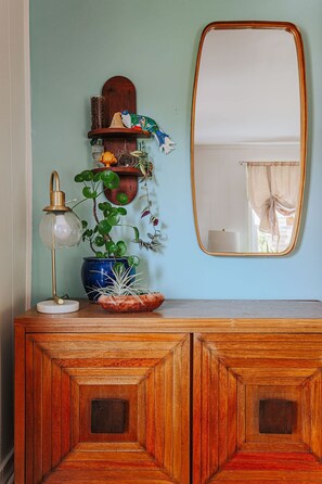 Un meuble en bois avec un miroir, une lampe et des plantes décoratives.