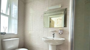 A bathroom with a toilet, sink, mirror, and a window. - Belgravia Holiday Apartments No 4 (Torquay)