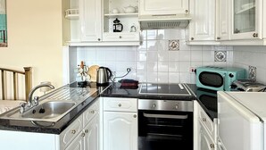 A kitchen with white cabinets, a black countertop, a coffee maker, a toaster, and a microwave. - Belgravia Holiday Apartments No 4 (Torquay)
