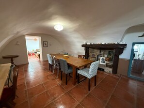 Ein Essbereich mit Holztisch und -stühlen, einem Kamin und einem gefliesten Boden.