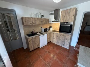 Eine kompakte Küche mit Holzschränken, einem Geschirrspüler, einer Mikrowelle und einem Bosch-Backofen.