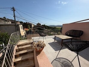 Una terrazza sul tetto con tavolo, sedie e una pianta in vaso.