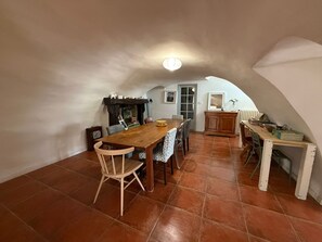 Zona pranzo in sottotetto con tavolo in legno, sedie e un piccolo armadietto.