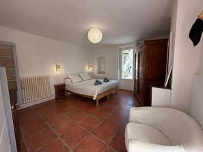 Ein Schlafzimmer mit Bett, Nachttischlampen, Heizkörper, Fenster und Kleiderschrank.