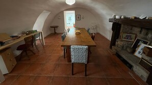 A dining area with a wooden table and chairs, a fireplace, and a view into another room. - Le Balcon des Pourcelles 12personnes /terrasses (Les Mées)