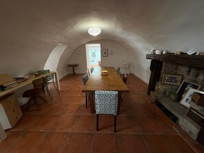 Zona pranzo con tavolo e sedie in legno, camino e vista su un'altra stanza.