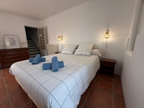 Camera da letto con un letto, una cassettiera, un termosifone, una scala e due lampade a parete.