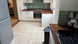 Una cocina funcional con estufa a gas, horno y un pequeño cubo de basura.