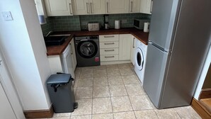 Una cocina compacta con lavadora, refrigerador y basurero.