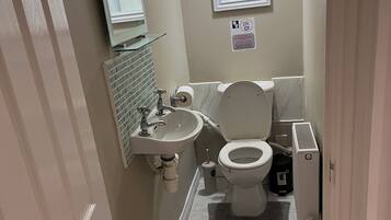 A bathroom with a toilet, sink, mirror, and ventilation system.