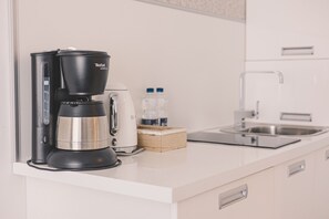 Eine moderne Küche mit einer schwarzen Kaffeemaschine, einem Toaster und zwei Wasserflaschen auf der Arbeitsplatte.