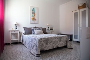 Een slaapkamer met een bed, twee nachtkastjes, een kledingkast en een muur met een enkel kunstwerk.