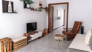 Ein Wohnzimmer mit Fernseher, Holzmöbeln, einem Sessel und einer Tür zu einem anderen Raum.