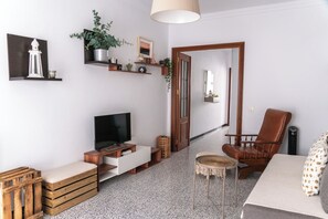 Ein Wohnzimmer mit Fernseher, Holzmöbeln, einem Sessel und einer Tür zu einem anderen Raum.