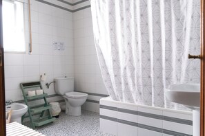 Ein Badezimmer mit Toilette, Bidet, Waschbecken und Duschvorhang.