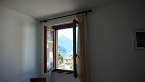 Une pièce avec une fenêtre, un rideau, une chaise et un tableau encadré accroché au mur.