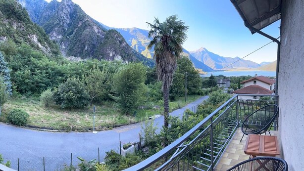 Un balcon avec vue sur les montagnes, un palmier et une route.