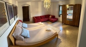 Ein Schlafzimmer mit einem gebogenen Bett, einem roten Sofa, einem Holzschrank und gerahmten Kunstwerken an der Wand.