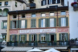 A building with a sign for 'Pizzeria,' 'Ristorante Almici,' and 'Bar Caffè.' - Stylish Lakefront House is a beautiful and spacious 2 bedroom apartment, with plenty of light coming from the big and many windows overlooking the lake and the harbor, the apartment boasts a Spacious lounge with breathtaking lake view where you can lay d (Lovere)