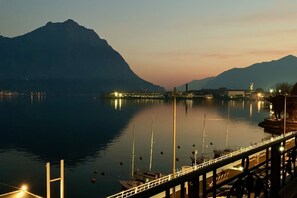Un lago tranquillo con un ponte, barche e montagne sullo sfondo.