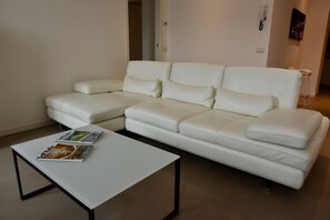 Ein weißes Ledersofa, ein weißer Couchtisch und eine Zeitschrift auf dem Tisch.