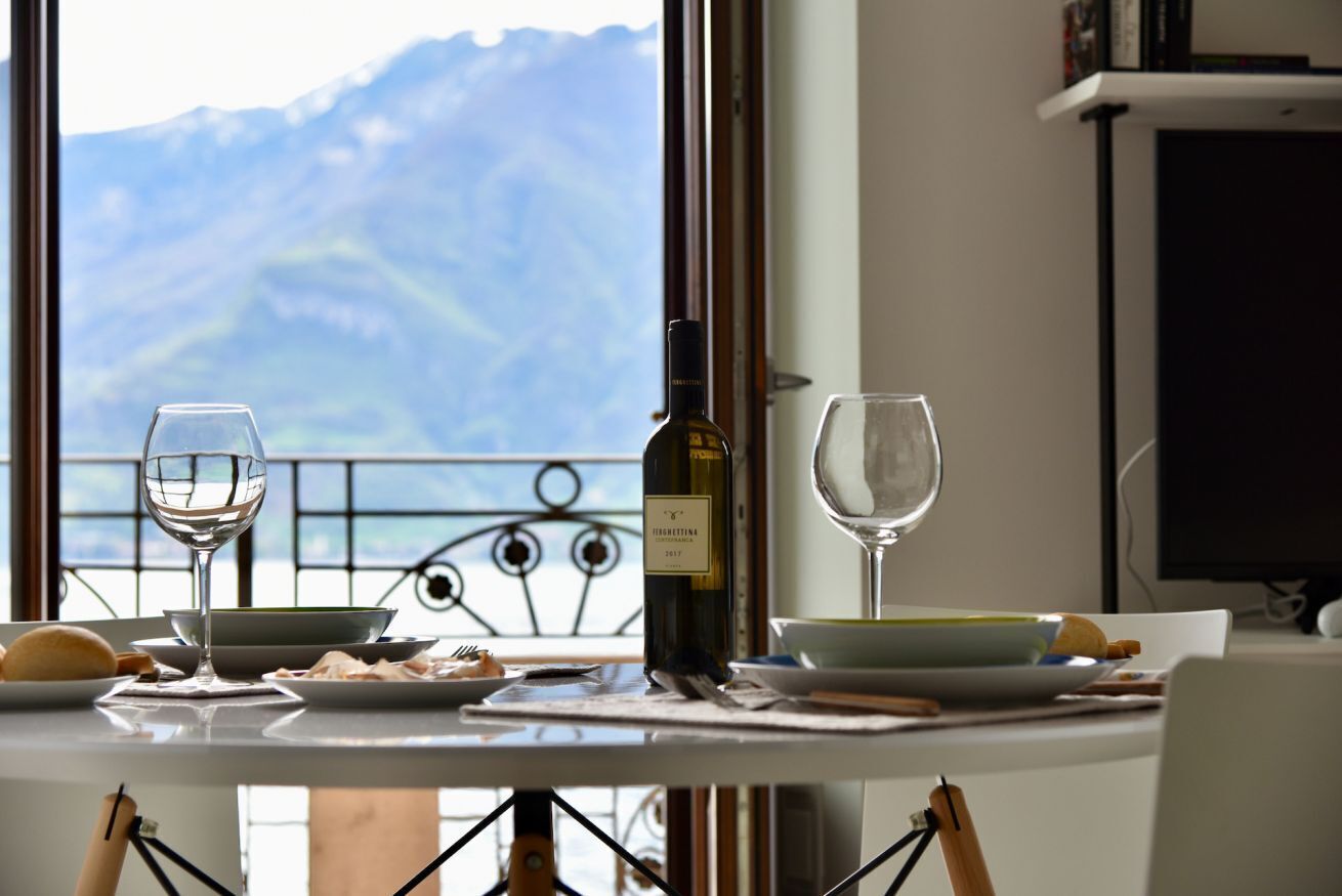 Un tavolo da pranzo con una bottiglia di vino, due bicchieri e piatti di cibo, con vista sulle montagne.