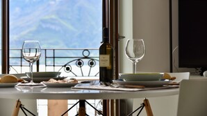 Un tavolo da pranzo con una bottiglia di vino, due bicchieri e piatti di cibo, con vista sulle montagne.