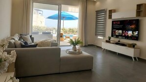 Un salon moderne avec un canapé, un téléviseur et une vue sur l’extérieur.