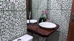 A bathroom with a wooden vanity, a white sink, and a mirror. - POUSADA MOAÇARA (Nobres)